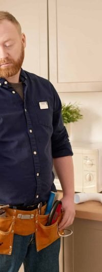 Repairman using work tools to fix sink and faucet during his work in domestic kitchen